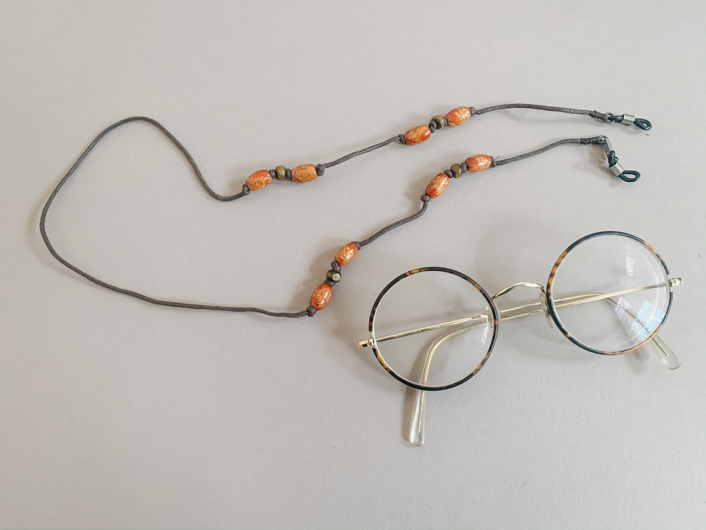 Glasses strap made with brown string and wooden beads.