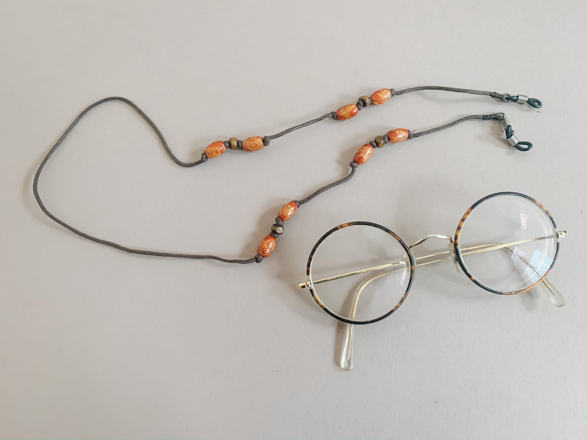 Glasses strap made with brown string and wooden beads.